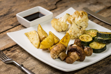 Roasted vegetables with sauce served on wooden table