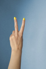 Two fingers with yellow nails on blue background