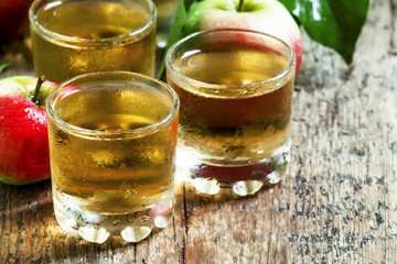 Cold apple juice and fresh apples on an old wooden table, select