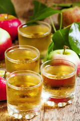 Cold apple juice and fresh apples on an old wooden table, select