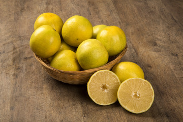 Close up of some oranges in a basket over a wooden surface