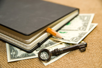 notebook, key, pencil and money on the old tissue © zheltobriukh