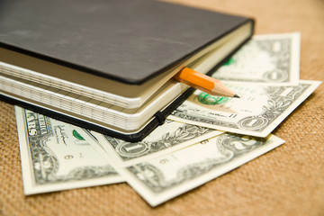 notebook, pencil and money on the old tissue