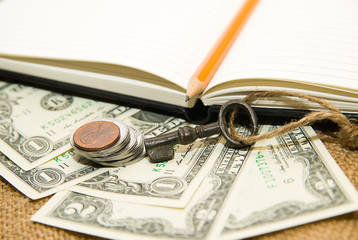 Opened notebook, pencil, key and money on the old tissue
