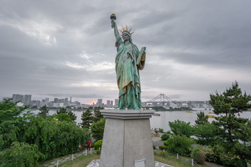 Fototapeta premium Statue of Liberty and Rainbow bridge in Odaiba at sunset