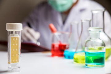 Laboratory research, lab glassware containing chemical with blur scientist 