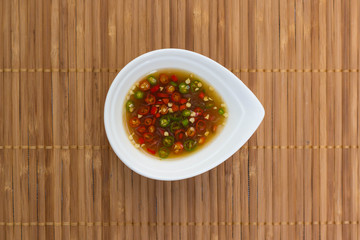 Fish sauce and chili in a cup on bamboo stick straw mat