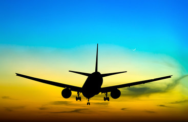 Plakat Silhouetted commercial airplane flying at sunset