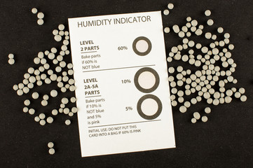 Humidity indicator card and humidity absorber desiccant balls isolated on the black background