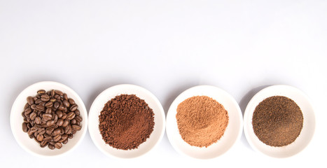 Coffee beans, powdered coffee, chocolate powder and processed tea leaves beverages in white bowl over white background