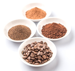 Coffee beans, powdered coffee, chocolate powder and processed tea leaves beverages in white bowl over white background