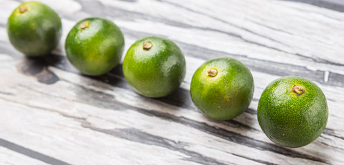 Calamansi citrus over weathered wooden background
