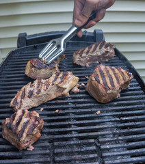 beef steaks being grilled for a family BBQ in summer