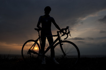 Silhouette of a biker with his bicycle at sunset
