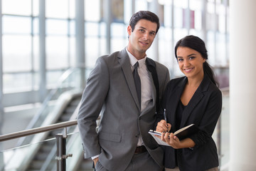 Business executive and assistant traveling at convention on a trip in the airport taking notes...