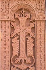 Fototapeta na wymiar Cross carved on red stone - armenian church