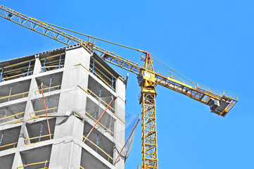 Crane and building construction site against blue sky