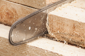 Motor chainsaw cutting wooden beam closeup