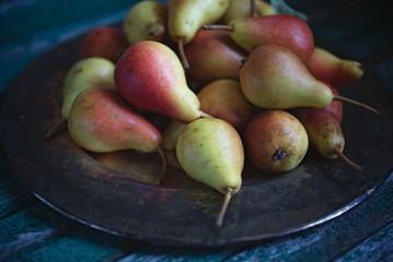 Ripe red and yellow pears, copper tray on an old wooden table