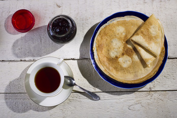 Pancakes with jam on a wooden background.