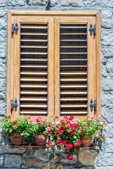 Fototapeta na wymiar Typical window of a stone house with wooden shutters closed and