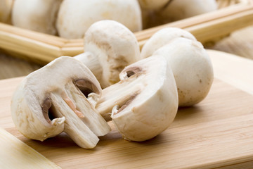 Mushrooms Cut in Halves – White button mushrooms. Front mushroom cut in half. Whole mushrooms in background.