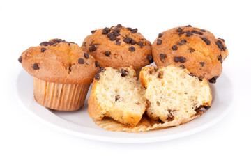 Plate of Chocolate Chip Muffins – Four chocolate chip muffins on a white plate. One muffin is split in half. On a white background.