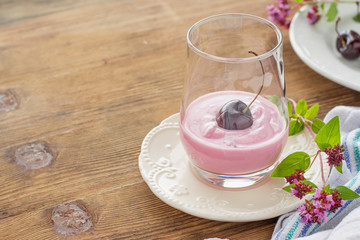 Cherry yogurt and ripe cherry with a sprig of marjoram