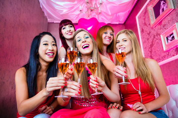 Braut und Freundinnen feiern Junggesellinnenabschied mit Sekt im Nachtclub