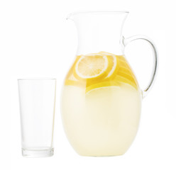 Lemonade pitcher with lemon slices and empty glass  isolated on