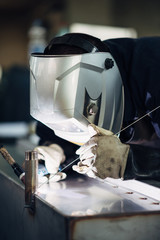 Welder at work using welding mask