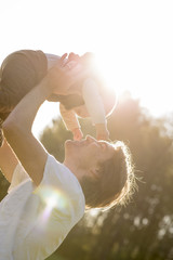 Fototapeta na wymiar Joyful young father lifting and kissing his baby boy