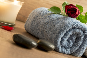 Fototapeta na wymiar Luxurious wellness arrangement with a rolled blue towel, red ros