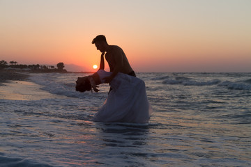 Fototapeta na wymiar Just married young couple on a hazy beach at dusk.