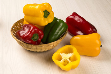 Some red, green and yellow peppers over a wooden surface