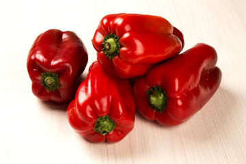 Some red, green and yellow peppers over a wooden surface