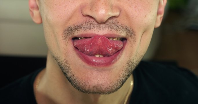 Unshaven man shows tongue and grimaces