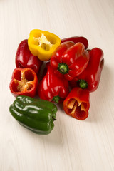 Some red, green and yellow peppers over a wooden surface