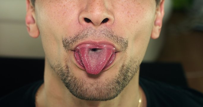 Unshaven man shows tongue