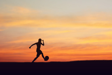 Silhouette of children playing soccer background sunset.