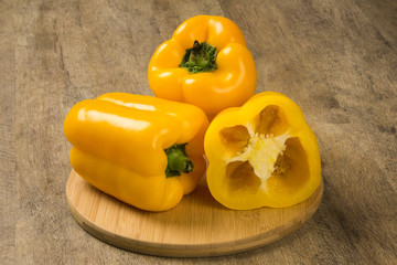 Some red, green and yellow peppers over a wooden surface