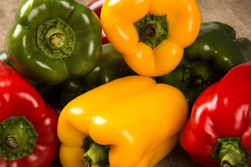 Some red, green and yellow peppers over a wooden surface