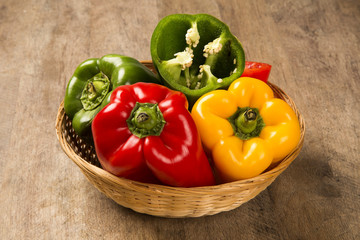 Some red, green and yellow peppers over a wooden surface