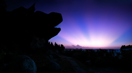 Naklejka premium Ray sunrise side of the dog's head rock with purple halo rhyme from horizon as dawn great moments. Photo taken at Ke Ga lighthouse, Binh Thuan.