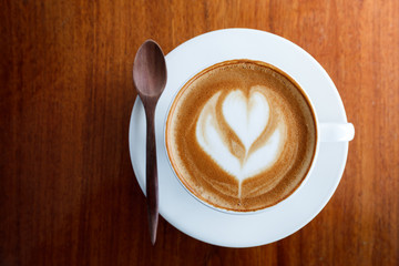 Cup of latte coffee and spoon on wooden