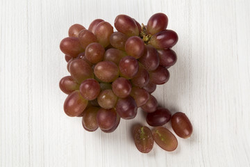 Some red grapes in a wooden pot over a wooden surface seen from