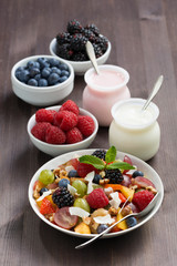 fruit salad, fresh berries and yoghurts on a wooden table