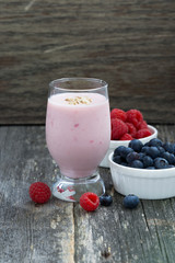 milkshake and fresh berries on the wooden background, vertical