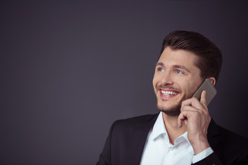 mann telefoniert mit seinem handy vor grauem hintergrund