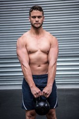 Obraz premium Portrait of muscular man lifting a kettlebell
